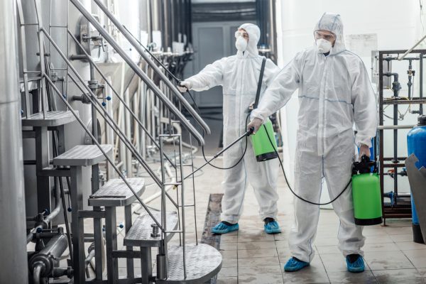 Covid-19,And,Sanitation.,Guys,In,Protective,Suits,And,Glasses,Disinfect